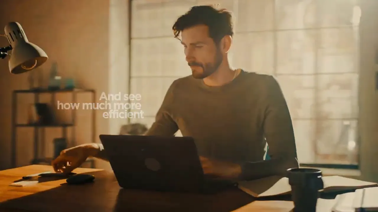 Person at desk using a laptop with notebook and coffee, warm lighting