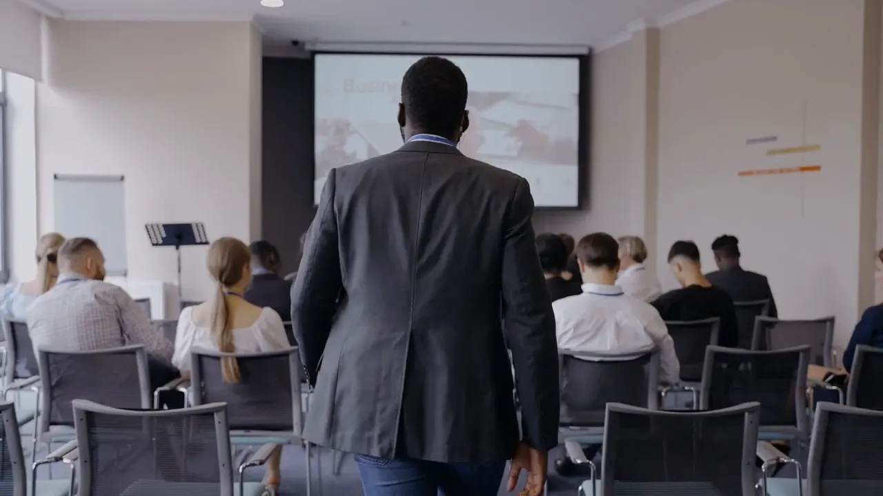 Rear view of a presenter walking toward a projection screen in a small classroom or workshop