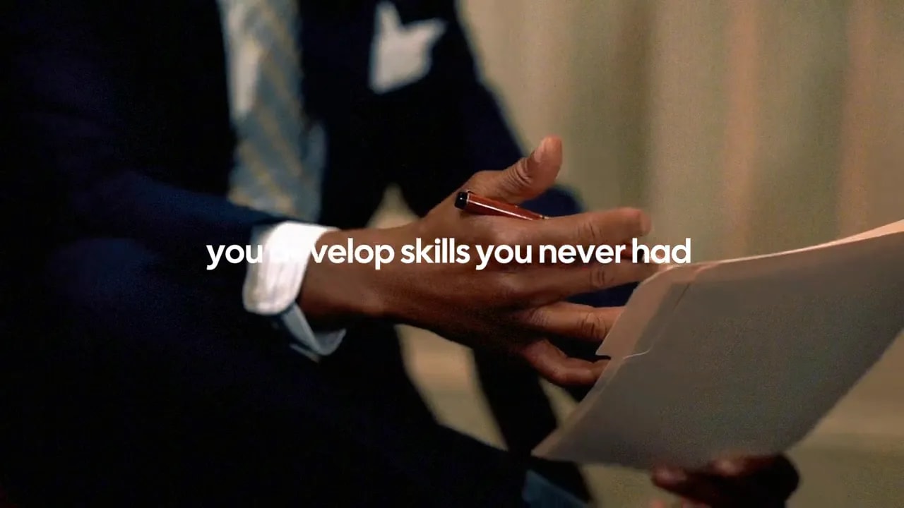 Close-up of a person handing a document while a pen is held, symbolizing learning and building transferable business skills.