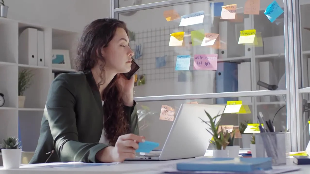 Professional working at a desk beside a wall covered with planning notes
