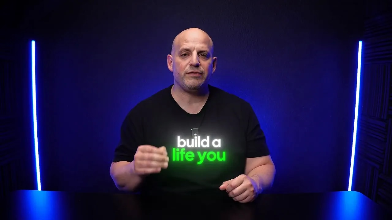 Business Ownership Coach gesturing while wearing a “builda life you” shirt in a studio setting