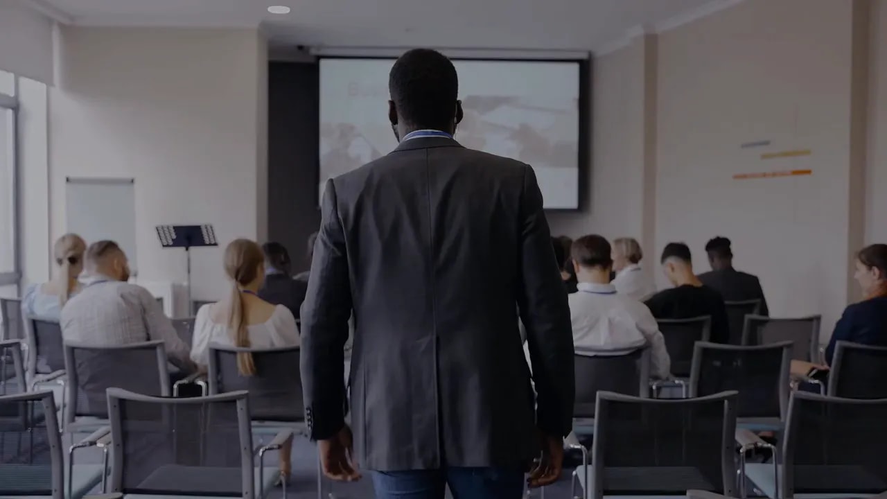 Business professional entering a room with seated attendees