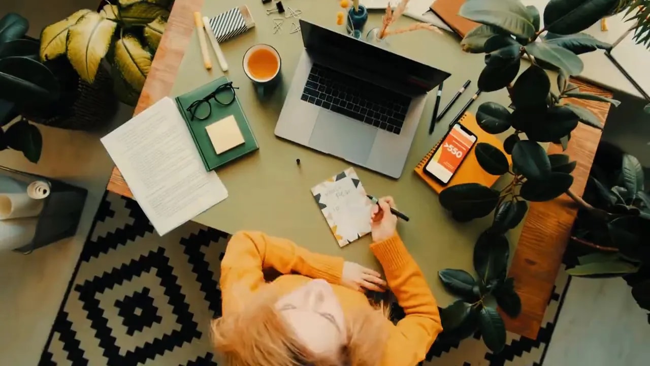 Person reviewing paperwork at a desk with laptop and office supplies