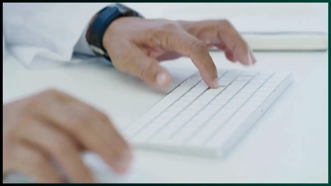 Hands typing on a white keyboard at a desk