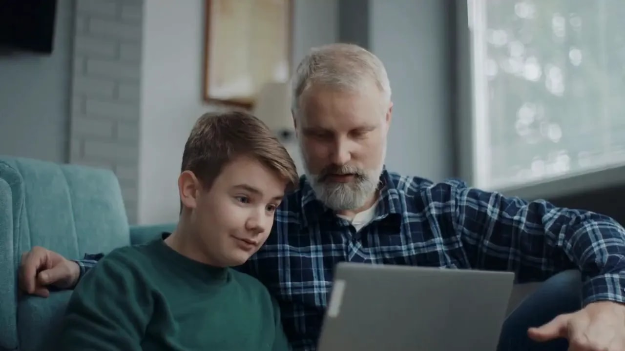 Father and son looking at a laptop together on a couch