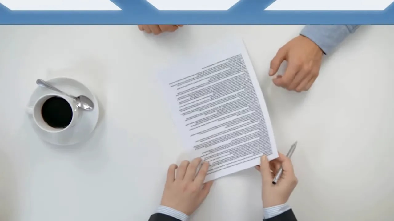 Hands pointing at a document on a table beside a cup of coffee