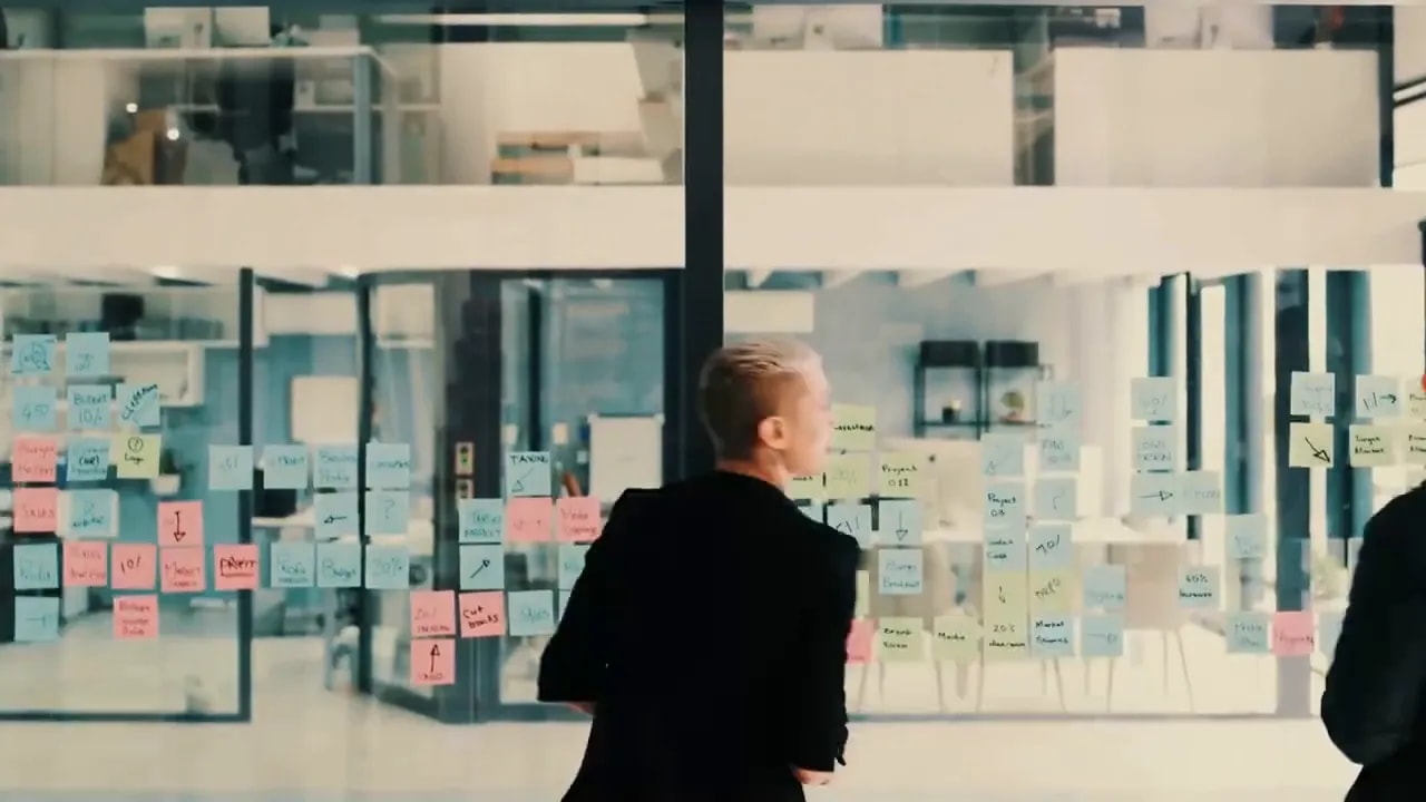 Business leader reviewing planning visuals on a shared glass wall with sticky notes