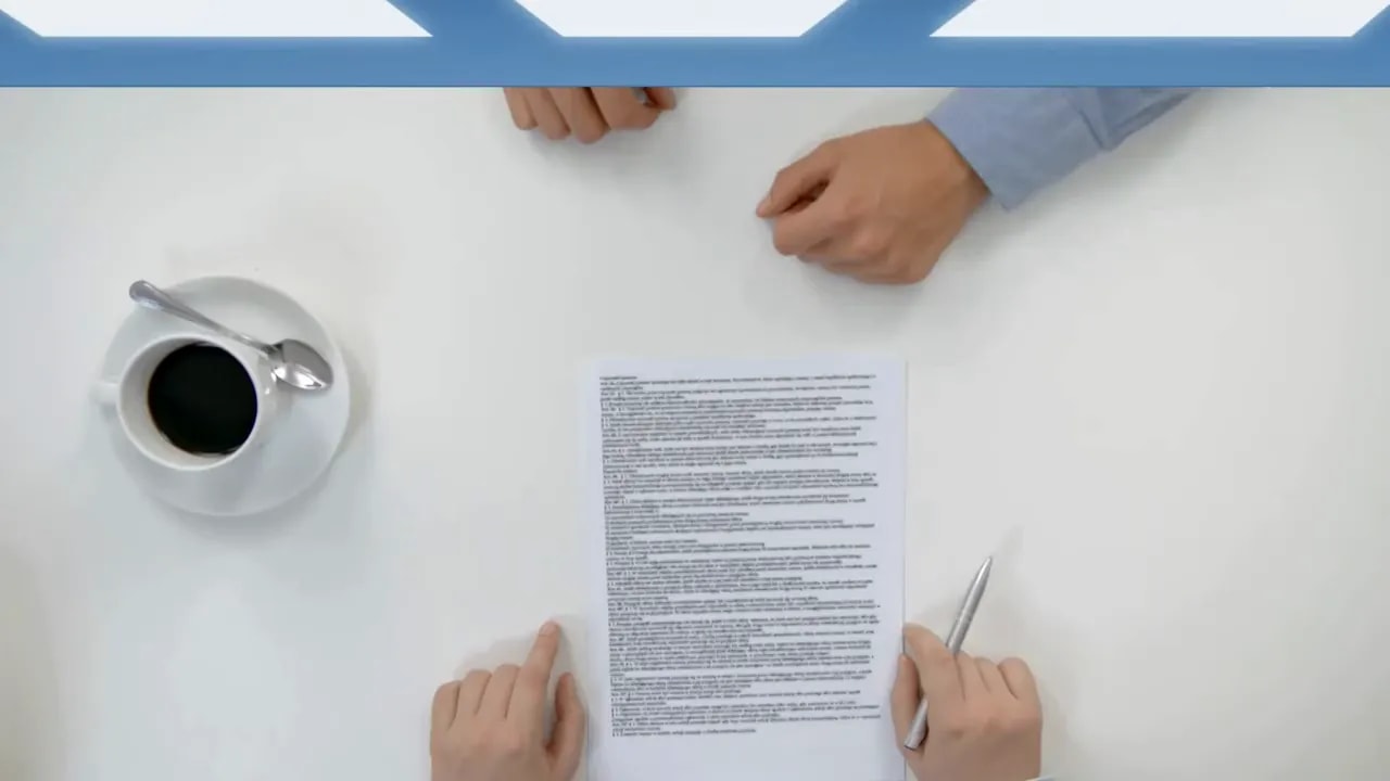 Hands reviewing a printed document on a white table