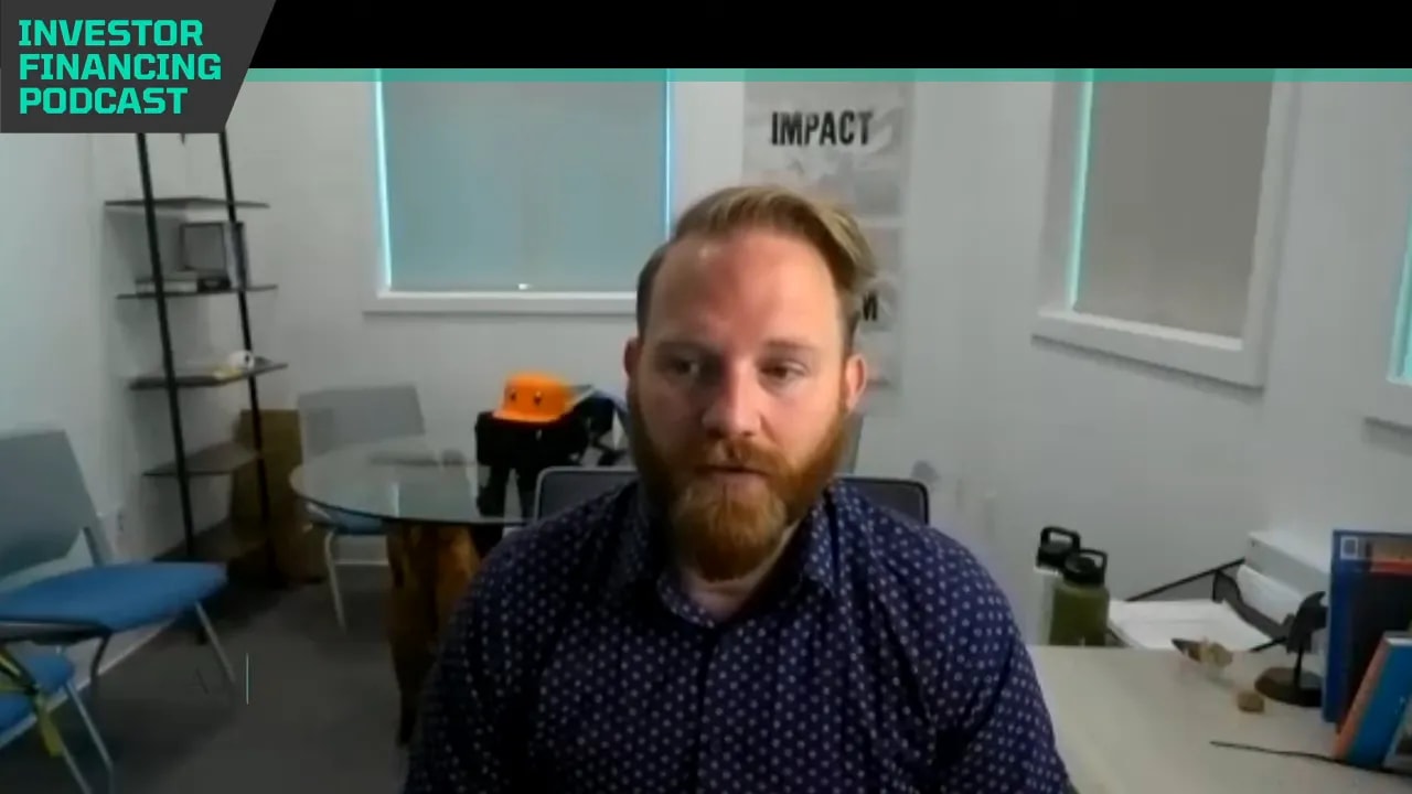 podcast guest framed at desk in an office with 'Investor Financing Podcast' banner visible