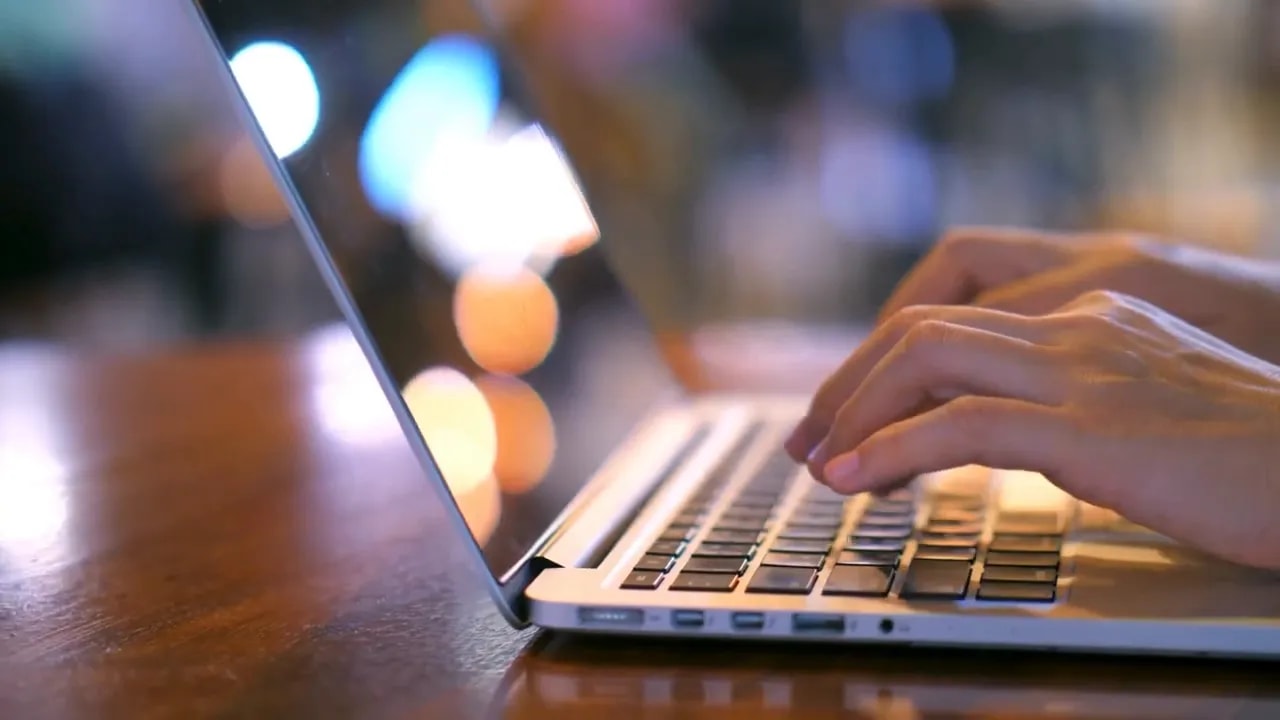 Hand using a laptop keyboard while working at a desk