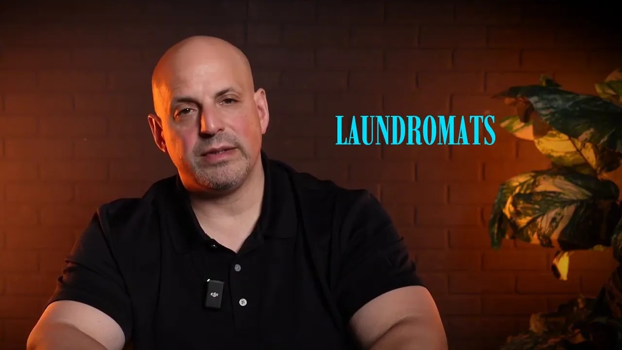 Presenter in interview set with on-screen title 'LAUNDROMATS' highlighting the laundromat model.