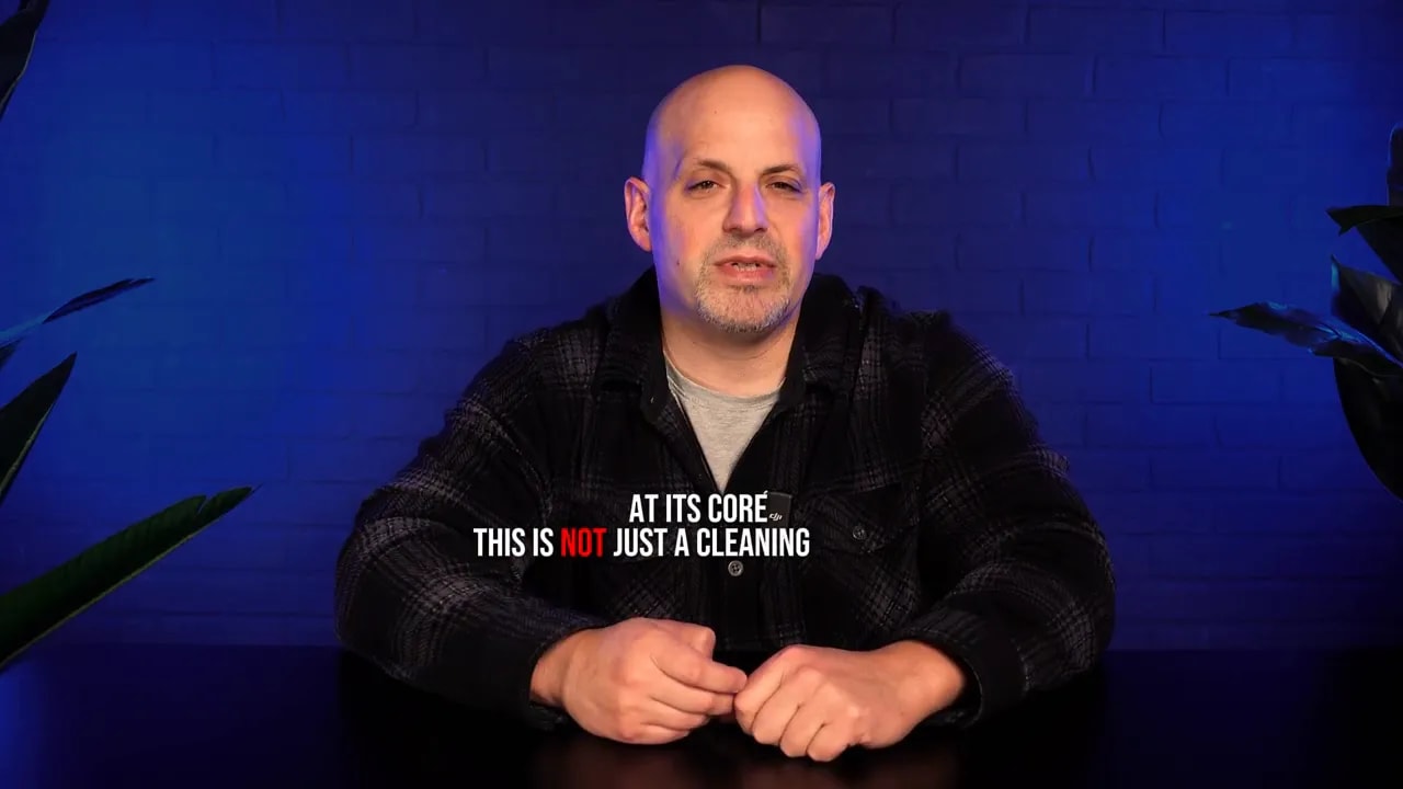 Presenter centered on blue background with clear on-screen text reading 'AT ITS CORE THIS IS NOT JUST A CLEANING'.