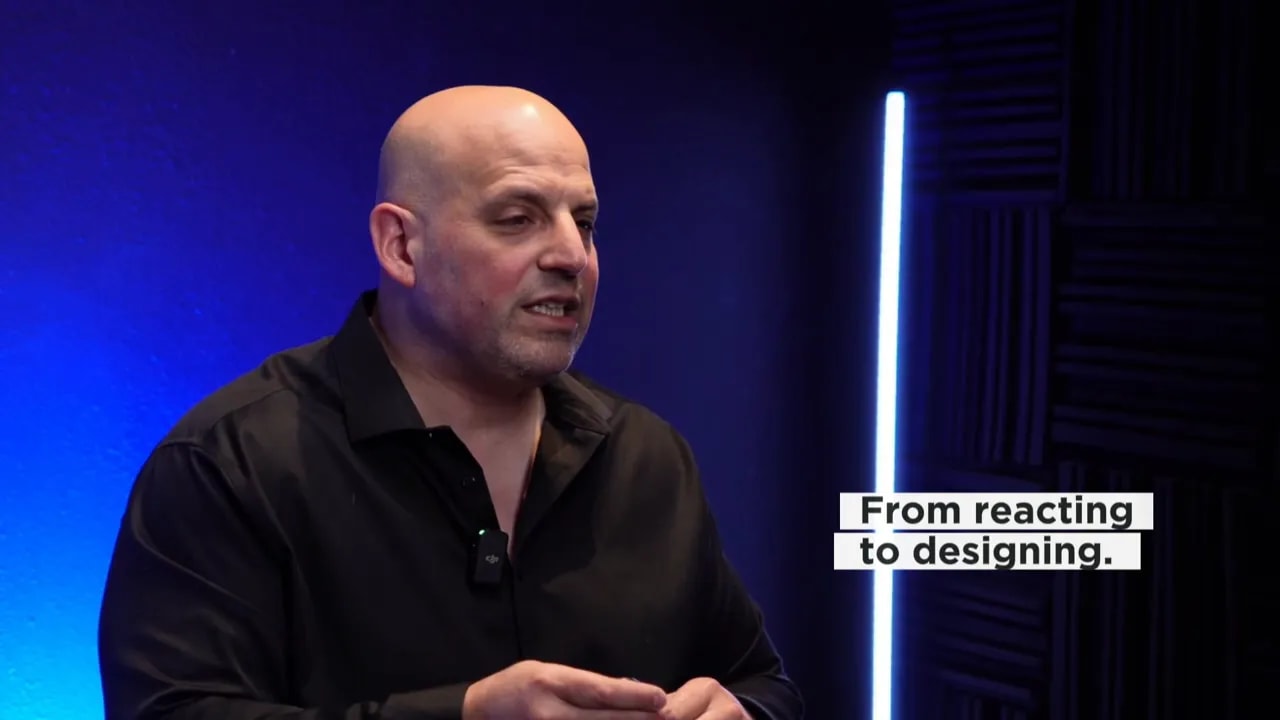 On-screen text showing a shift from reacting to designing