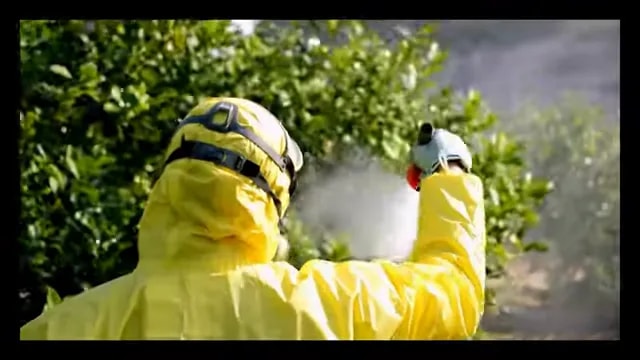 Pest control worker spraying outdoors in protective clothing