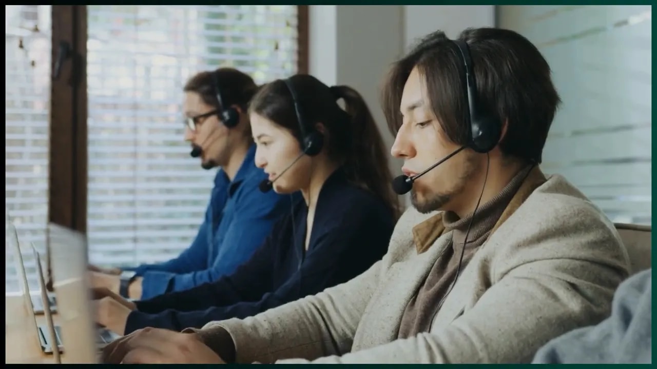 Three customer service professionals wearing headsets at computers