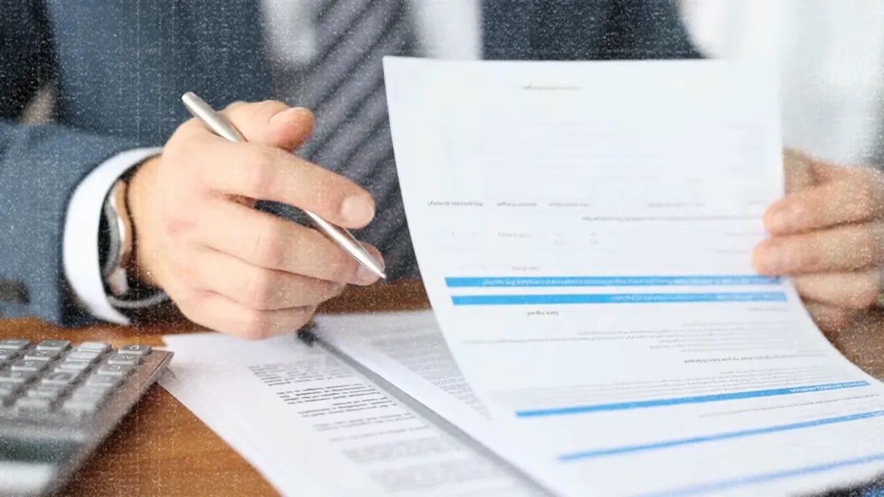 Hands reviewing a business document with a pen and calculator