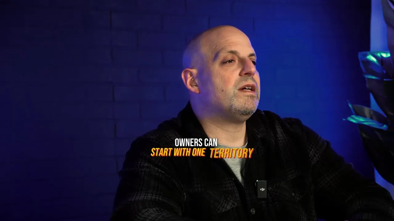 Presenter with overlaid text 'Owners can start with one territory', blue background